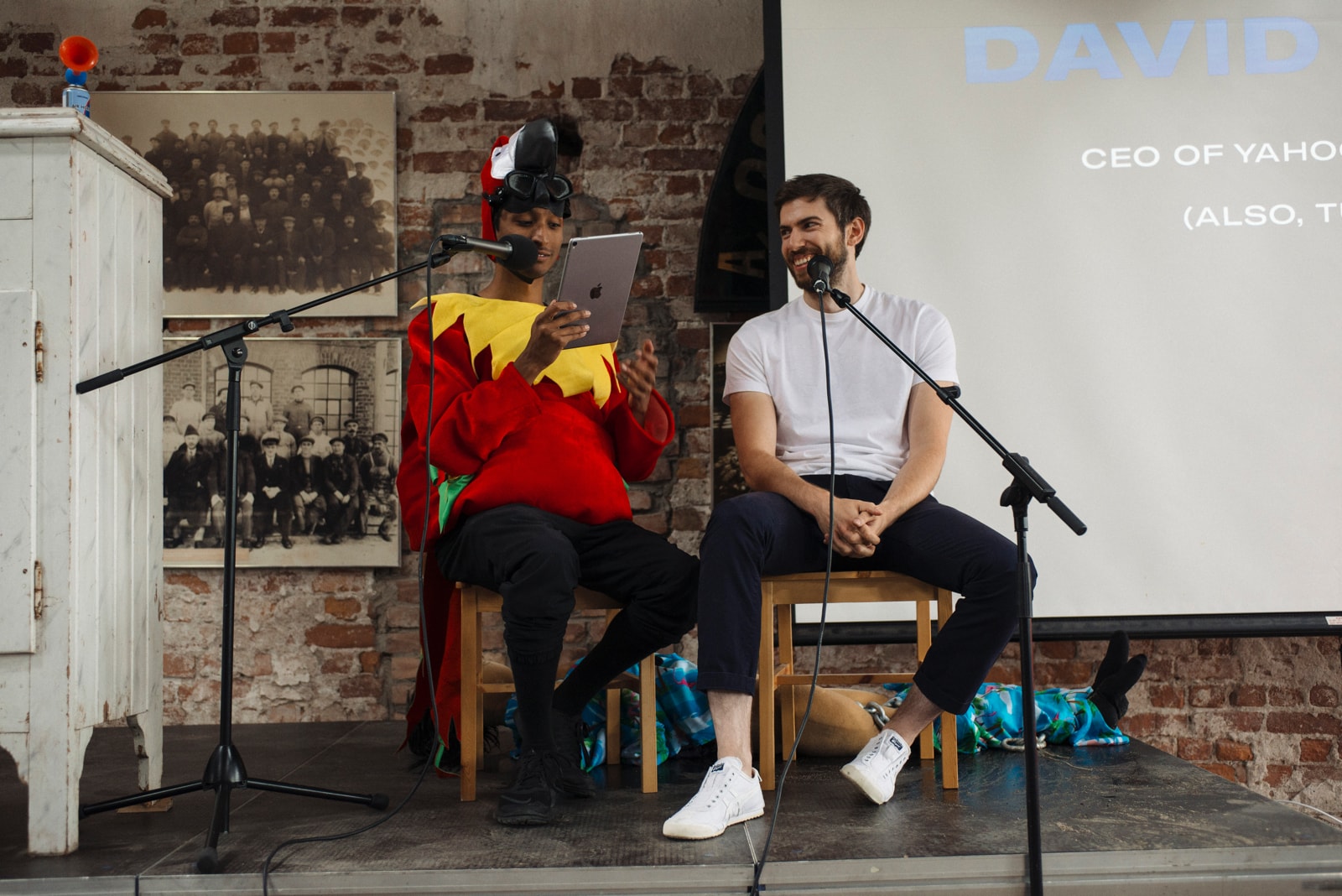 Pasqual on stage, wearing a bird suit, interviewing David Karp.