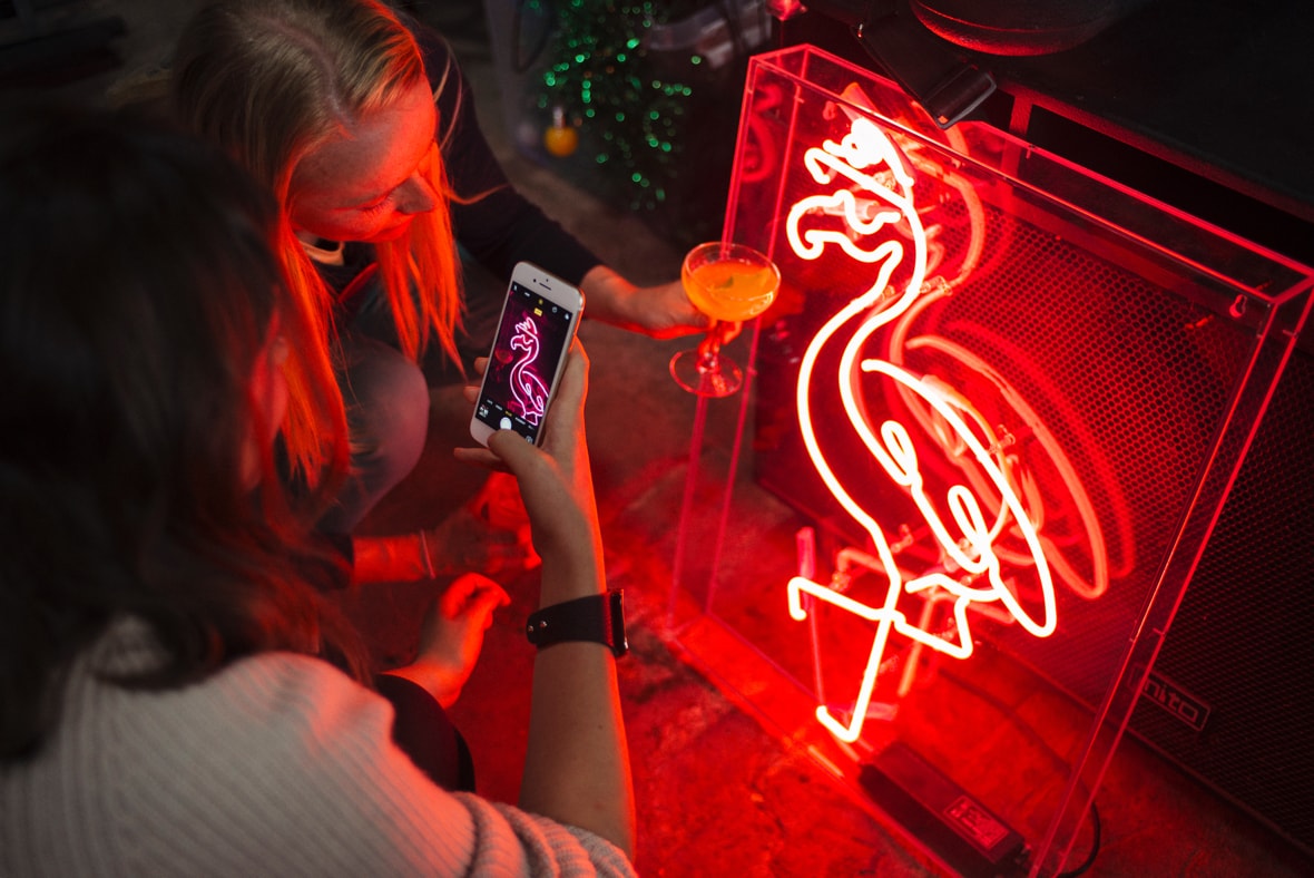 People taking pictures of a flamingo led-lamp